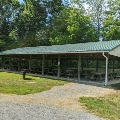 The picnic shelter at McCoy Park has a row of trees in the back and a gravel ADA accessible path in the front.